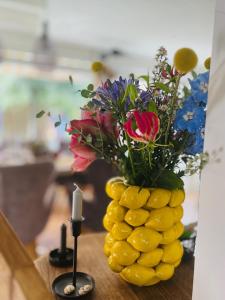 een vaas gevuld met bloemen op een tafel met een kaars bij "Zonnekind" Atmospheric holiday home in Noordwijkerhout near the beach in Noordwijkerhout