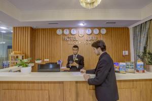 deux hommes debout à un comptoir dans un hall dans l'établissement Hotel Lulu, à Bishkek