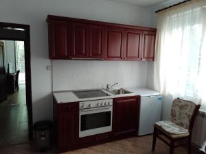 a kitchen with wooden cabinets and a stove and a sink at Цвят бяло in Sofia