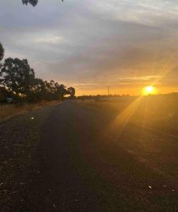 uma estrada vazia com o pôr-do-sol ao fundo em Hideaway Homestead em Nagambie