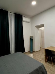 1 dormitorio con cama, escritorio y cortinas en Antico Borgo Rooms en Nápoles