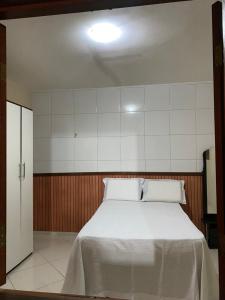 a bedroom with a white bed with two pillows at Casa GMafra in Rio de Contas