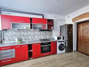 a kitchen with red cabinets and a refrigerator at Central Station Apartment in Cluj-Napoca