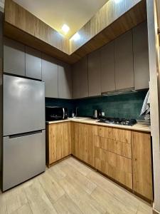 uma cozinha com armários de madeira e um frigorífico branco em Downtown Apartment em Kutaisi