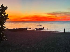 a person standing on a beach with two boats at White Beach Front and Cottages in Buruanga