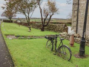 a bike parked in the grass next to a stone wall at High Shaftoe in Longwitton