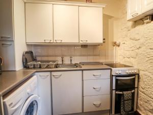 Longwitton的住宿－The Barn，厨房配有白色橱柜、水槽和洗碗机。