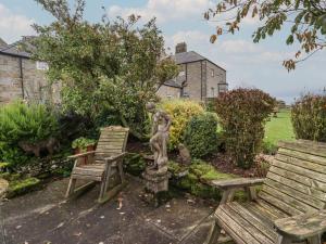 Longwitton的住宿－The Barn，花园内两个长椅和一个雕像