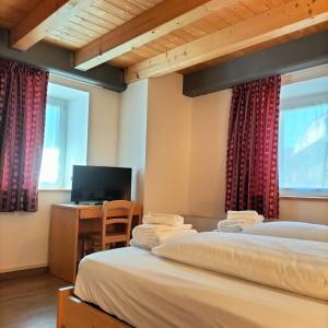 two beds in a room with a desk and a television at Cà Soldati in Campi
