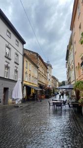 a city street with tables and buildings on a rainy day at Apartments of Lesya Ukrainka St. 25 in Lviv