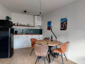 een keuken met een tafel en stoelen en een koelkast bij Apartment Duinvos 150m from the beach in Noordwijk aan Zee