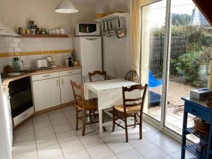 Una cocina con mesa y sillas y un refrigerador. en Maisonnette 3 chambres - Plage de Belmont, en La Turballe