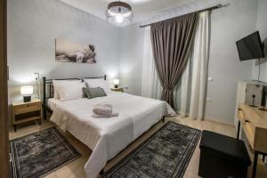 a bedroom with a large white bed and a television at Trikala Home in Tríkala