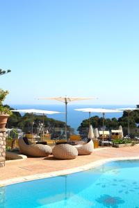 a swimming pool with chairs and umbrellas and the ocean at Hotel La Floridiana in Capri