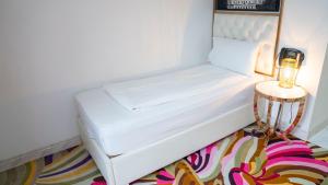 a white bed in a room with a side table at A Hotels Glostrup in Glostrup