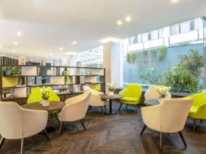 a library with yellow chairs and tables and bookshelves at Mercure Roma West in Mostacciano
