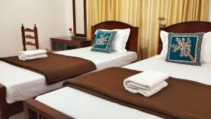 a hotel room with three beds with towels on them at KOVIL home's Guest land in Cochin