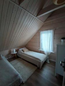 a attic room with two beds and a window at Arimaičių kaimo sodyba 