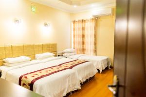 three beds in a hotel room with white sheets at Abuharee Grand in Hithadhoo