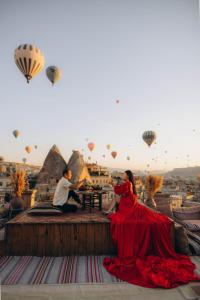a group of people sitting on a ledge with hot air balloons at Sultan Cave Suites in Göreme