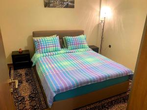 a small bedroom with a bed with colorful sheets and pillows at Helen's House in Tríkala +3 photos