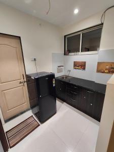 eine Küche mit einem schwarzen Kühlschrank und einer Spüle in der Unterkunft Gandhi Villa in Daman