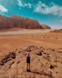 a person standing on a rock in the desert at Wadi rum camp in Wadi Rum