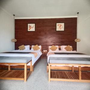 two beds in a room with wooden walls at THE OWN PENIDA COTTAGE & SPA in Nusa Penida