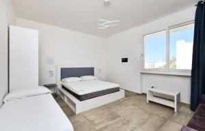 Damavi suite 3 في توري ديل أورسو: غرفة نوم بيضاء بسريرين ونافذة