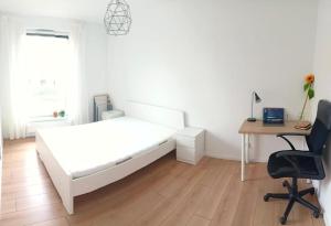 a white bedroom with a bed and a desk and a computer at YOURAPART Letnicka Sea in Gdańsk