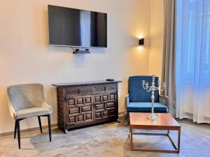 uma sala de estar com uma televisão, uma cadeira e uma mesa em Bazaar Boutique Residence em Budapeste