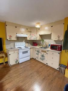 una pequeña cocina con electrodomésticos blancos y suelo de madera. en Lu Yao Inn OP en Calgary