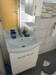 La salle de bains est pourvue d'un lavabo blanc et d'un miroir. dans l'établissement Sobe Sky, à Fužine