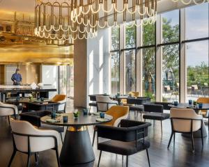 a restaurant with tables and chairs and a chandelier at Hyatt Centric Lakeside Ningbo in Ningbo