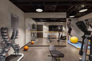 a room with a gym with a woman on a treadmill at Vienna House Easy by Wyndham Osnabrück in Osnabrück