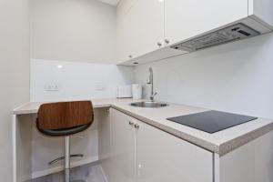 a white kitchen with a sink and a chair at Studio Flat West End Lane in London