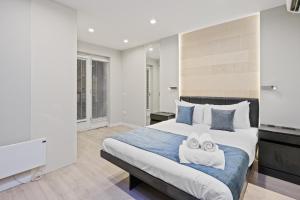 a bedroom with a large bed with two towels at Studio Flat West End Lane in London