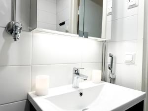 a white bathroom with a sink and a mirror at Aurora City Suite in Rovaniemi