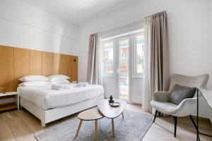 ein Schlafzimmer mit einem Bett, einem Stuhl und einem Tisch in der Unterkunft Elia Kolonaki Luxury Apartments in Athen