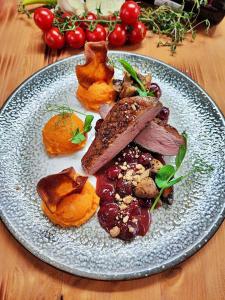 a plate of food with meat and vegetables on a table at Nelson Hotel in Hajdúszoboszló