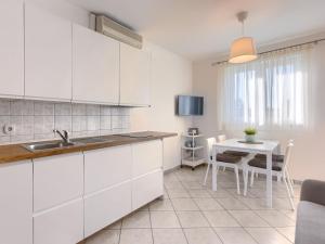 a kitchen with white cabinets and a small table at Apartment Fiore-2 by Interhome in Gedići