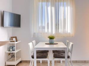 a white dining room table with white chairs and a tv at Apartment Fiore-2 by Interhome in Gedići