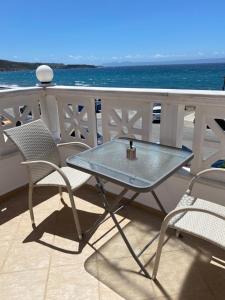 Ein Tisch und Stühle auf einem Balkon mit Meerblick in der Unterkunft Orsalia's Apartment in Neapolis