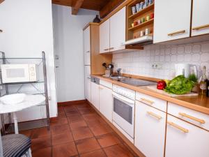 eine Küche mit weißen Schränken und Gemüse auf der Theke in der Unterkunft Holiday Home Sonnenschein by Interhome in Norddeich