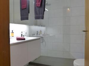 La salle de bains blanche est pourvue d'un lavabo et de toilettes. dans l'établissement Apartment Chalet Burgfeld by Interhome, à Beatenberg