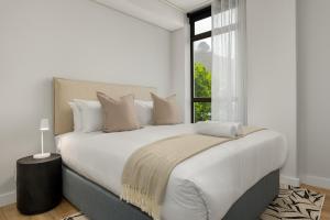 a white bedroom with a large bed with a window at Suro Luxury Apartments in Cape Town