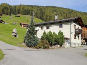 a large white building with a hill in the background at Apartment Haus Chumma Apt1 by Interhome in Frauenkirch