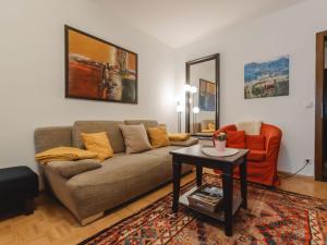a living room with a couch and an orange chair at Apartment FeWo Sun & Snow by Interhome in Bad Hofgastein