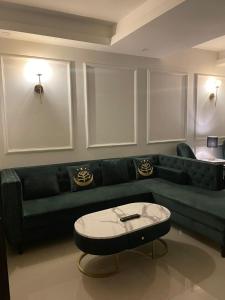 ein Wohnzimmer mit einem grünen Sofa und einem Tisch in der Unterkunft French 2-bed in Rawalpindi