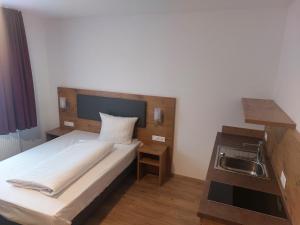 a small bedroom with a bed and a sink at Hotel Stern in Gersthofen